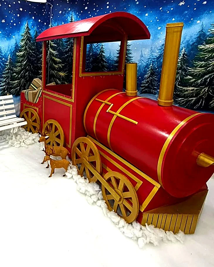 Locomotiva vermelha e dourada do cenário do trem, com renas e neve